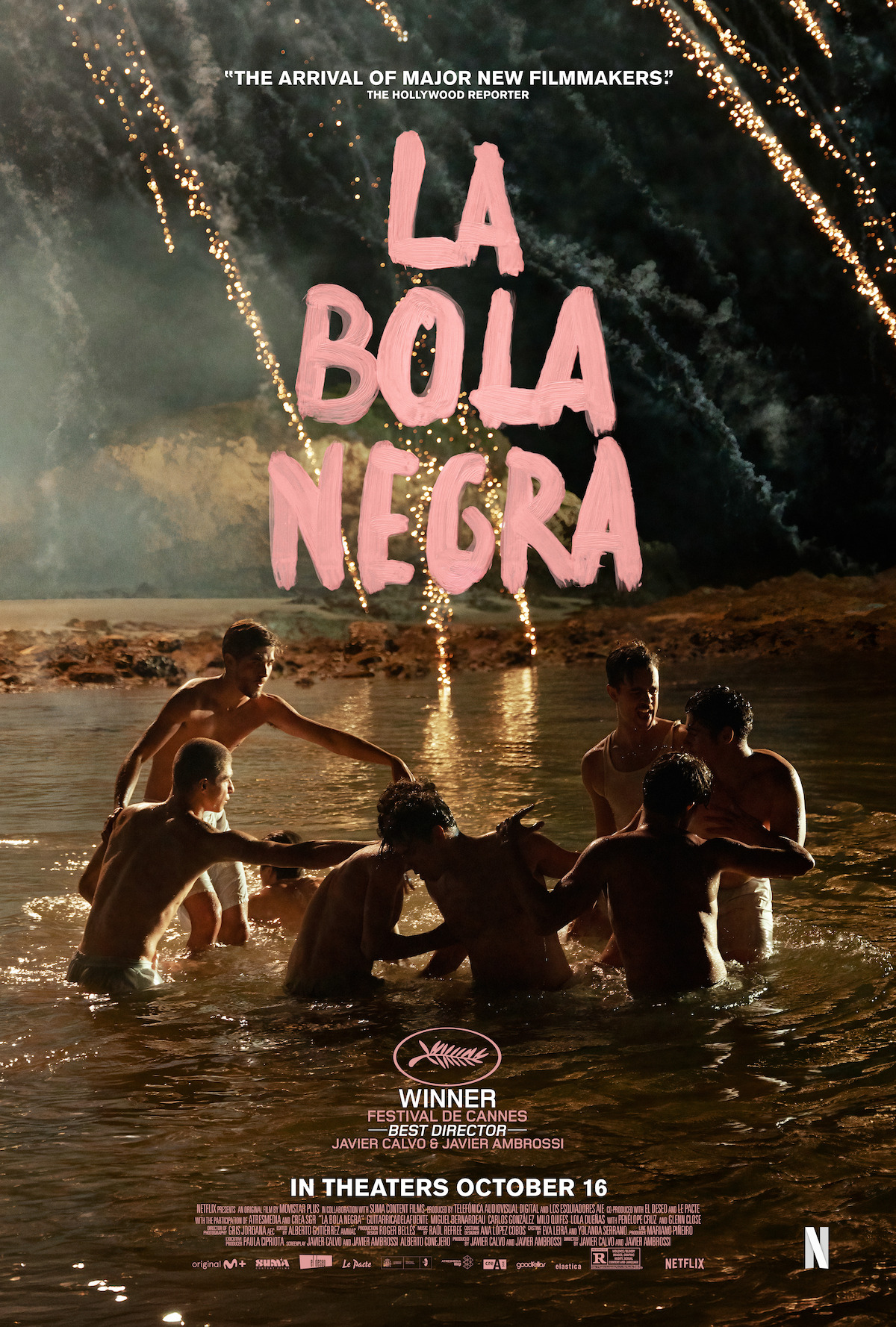 Six people stand waist-deep in water at night under fireworks, reaching towards the center. The environment is natural with a dramatic sky, and the mood is intense. Title text “La Bola Negra” and release info are overlaid.