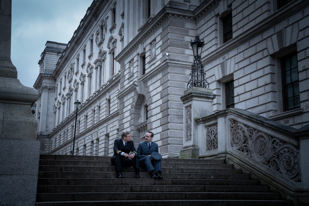 Two main characters sit on the steps of a government building in 'Operation Mincemeat'