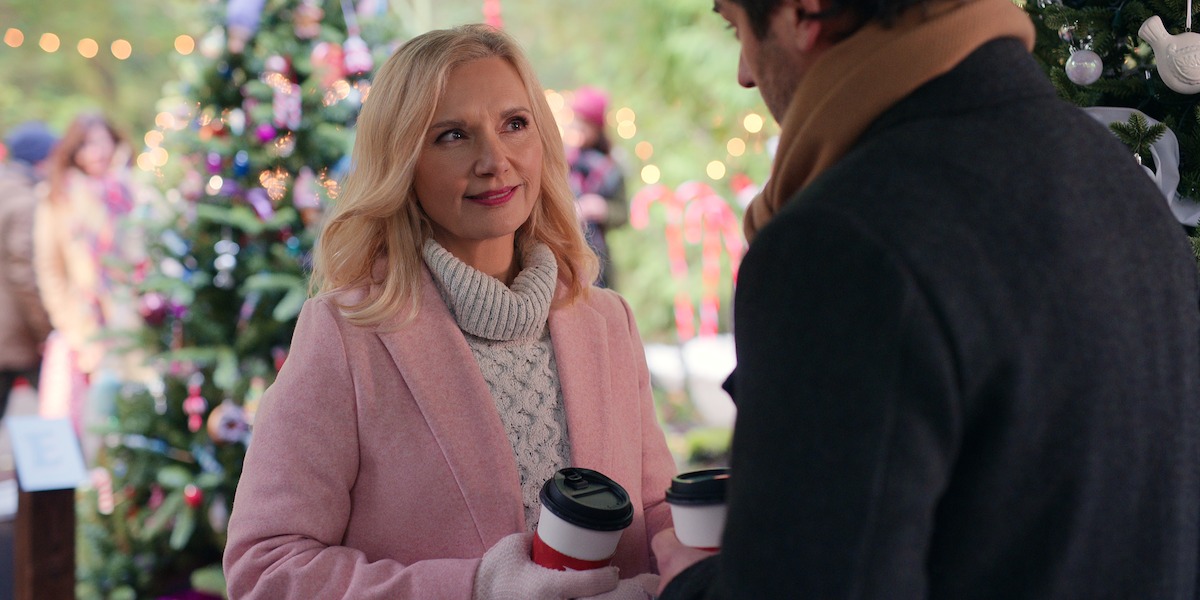 Teryl Rothery as Muriel St. Claire wears a pink coat at a Christmas market in Season 5 of ‘Virgin River’
