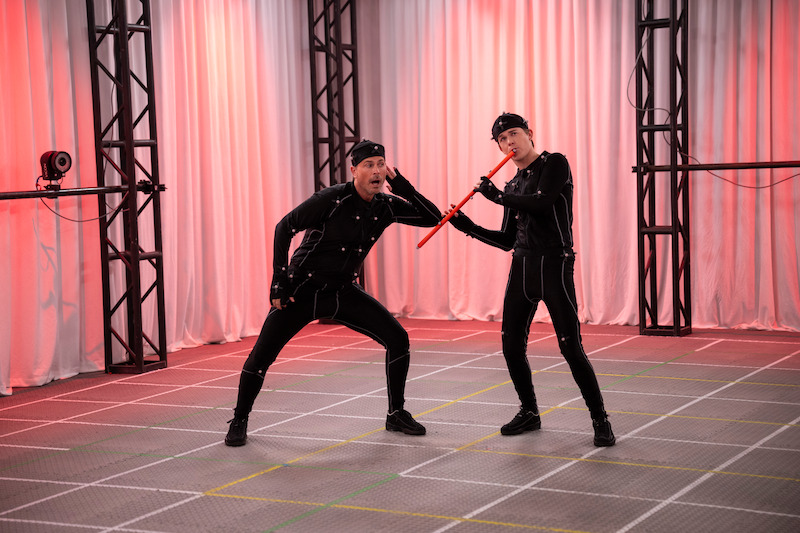 Rob Lowe as Ellis Dragon and John Owen Lowe as Jackson Dragon stand in a studio wearing motion capture suits in Season 2 of 'Unstable'