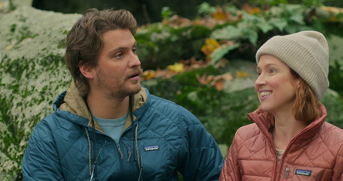 Ellie Kemper and Luke Grimes hike in the woods in a still from the new film 'Happiness for Beginners.'