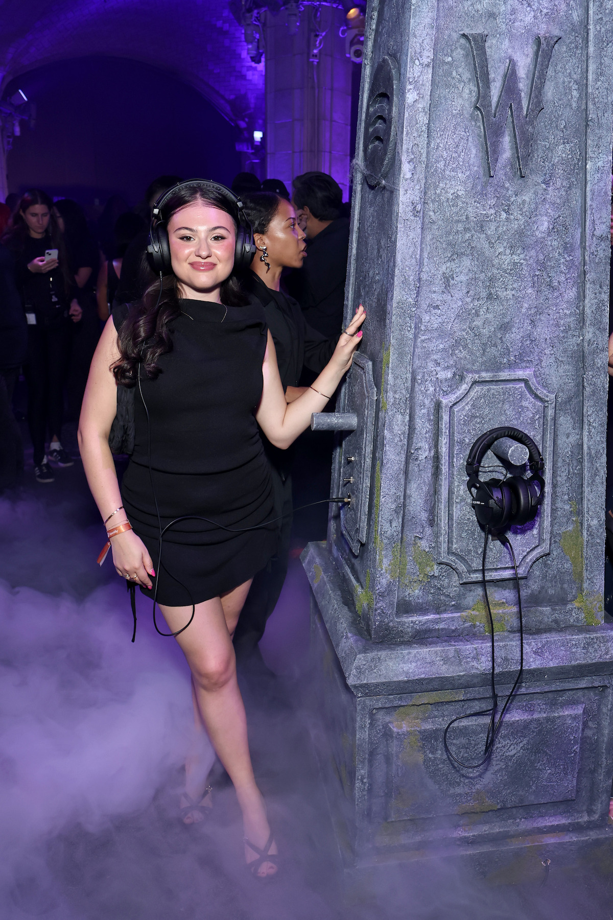 A fan wears headphones and poses for a photo at the Netflix x Spotify ‘Wednesday’ Season 2 Graveyard Gala.
