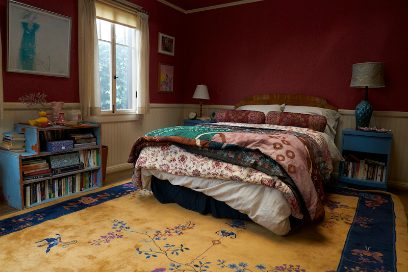 Bedroom with red walls and yellow rug.