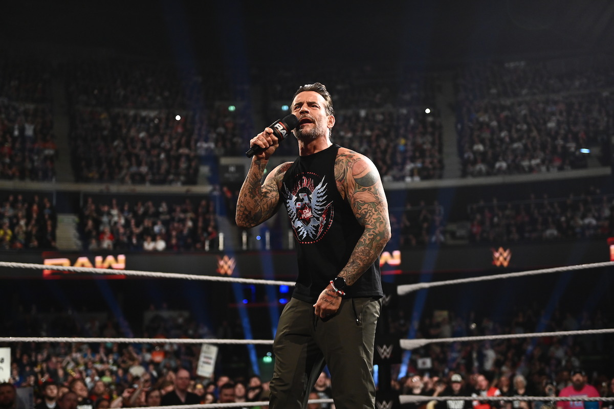 CM Punk speaks into a microphone in the ring.