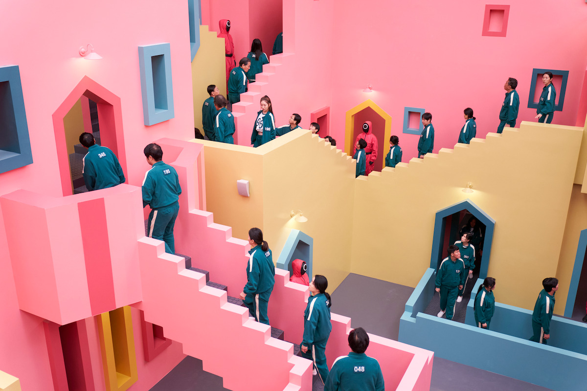 Players in green tracksuits navigate pink and yellow staircases in ‘Squid Game’ Season 2.