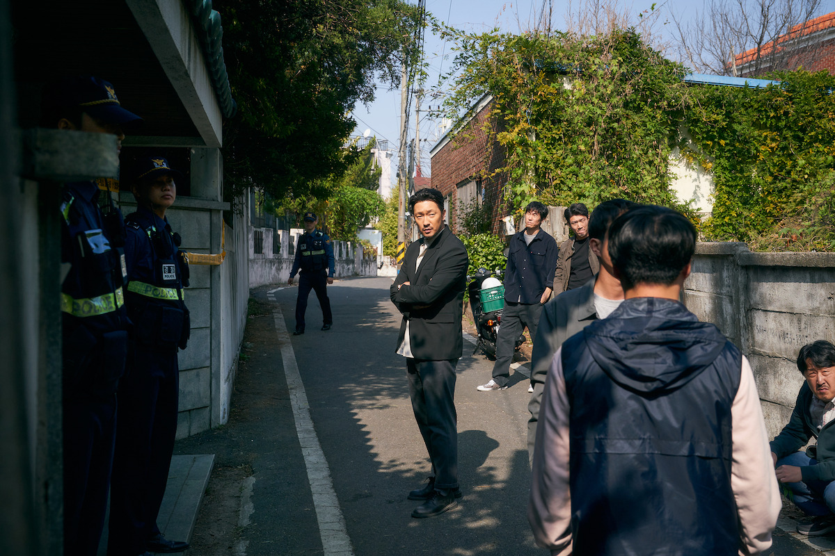 Son Suk-ku as Jang Nan-gam investigates at a crime scene in a still image from the series ‘A Killer Paradox.’