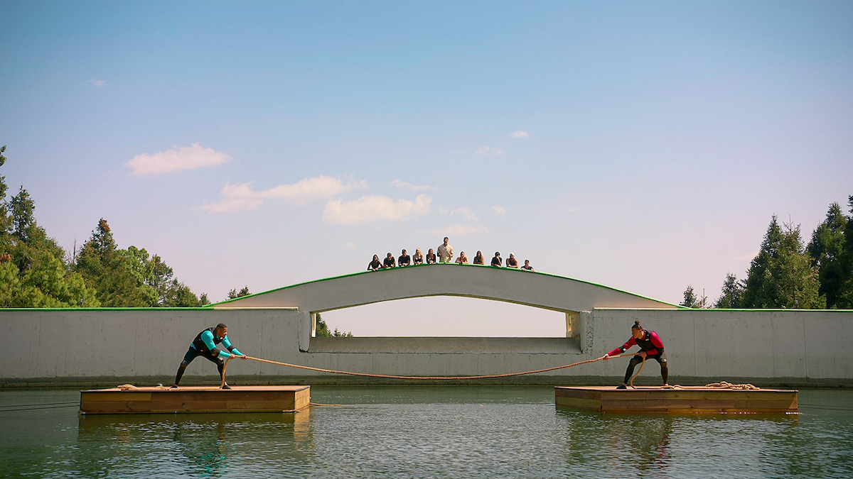 Players compete in a tug of war challenge on the water in 'Battle Camp'