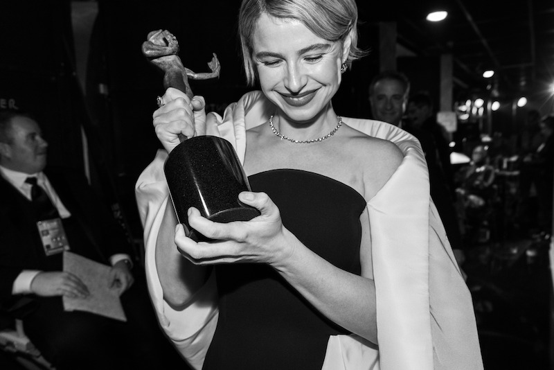 Jessie Buckley smiles with her eyes closed as she holds up her Actor Award.