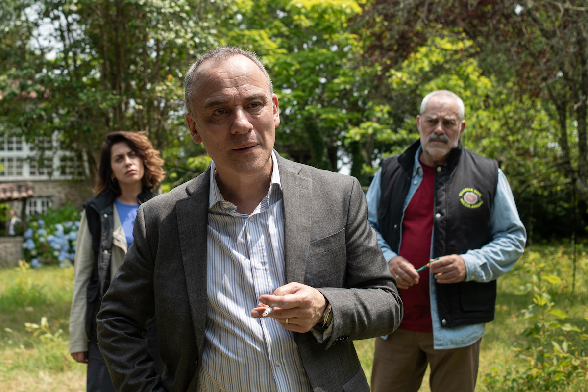 María León as Cruces, Javier Gutiérrez as Malvar, and Carlos Blanco as Ríos stand in a yard in an image from the series ‘The Asunta Case.’