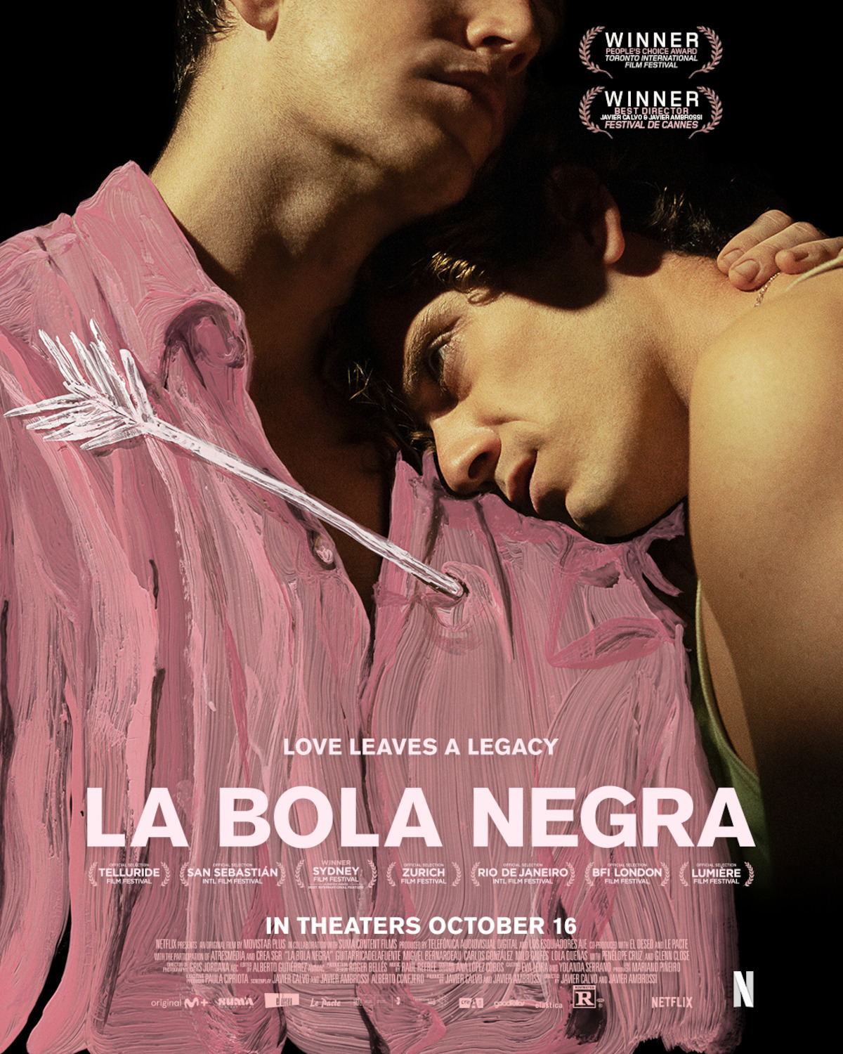Two men embrace in a dark, intimate setting with pink paint and a drawn arrow overlay. The poster text reads "LA BOLA NEGRA," highlighting love, legacy, and film festival awards, with a release date and credits at the bottom.
