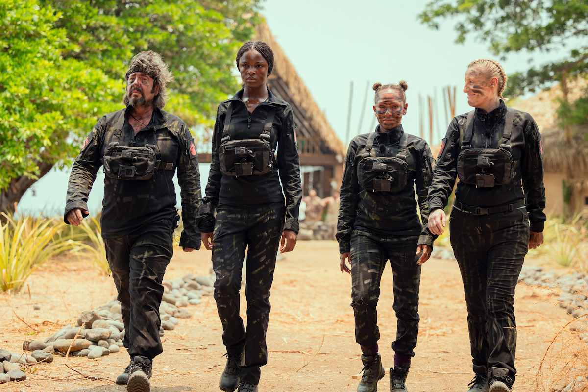 Mel B, Steph McGovern, Laurence Llewelyn-Bowen, and Leomie Anderson wear tactical gear and walk down a dirt path together in an image from the series ‘Celebrity Bear Hunt.’
