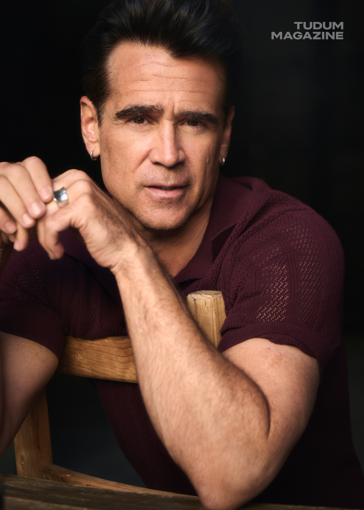 Colin Farrell looks directly at the camera while wearing a maroon polo.