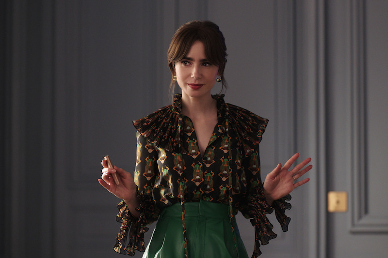 Lily Collins as Emily wears green pants and a dark blouse in Season 4 of 'Emily in Paris'