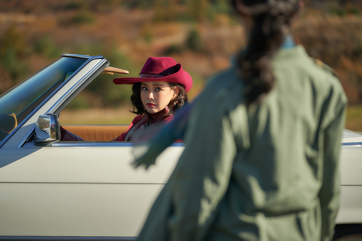 Hanee Lee as Jeong Hee-ran driving a convertible while Bang Hyo-Rin as Shin Ju-ae looks on in a production still from ‘Aema’.
