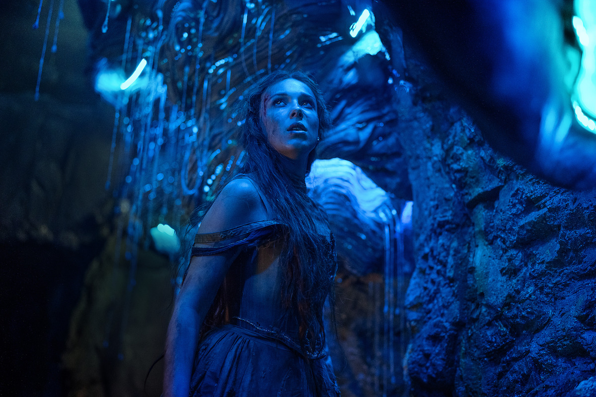 Millie Bobby Brown as Elodie in ‘Damsel’ stands in a cave.