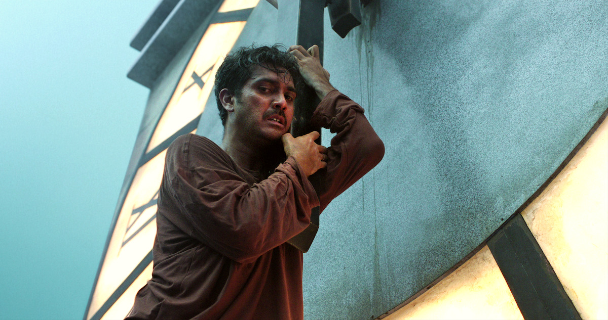 A man clings on to the hand of a giant clock tower in Season 1 of 'Joko Anwar’s Nightmares and Daydreams'