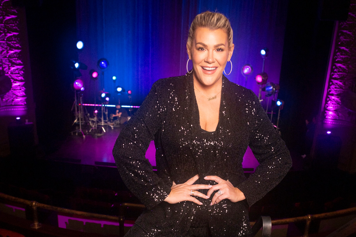 Heather McMahan stands in a theater in a black sequin suit in ‘Heather McMahan: Son I Never Had.’