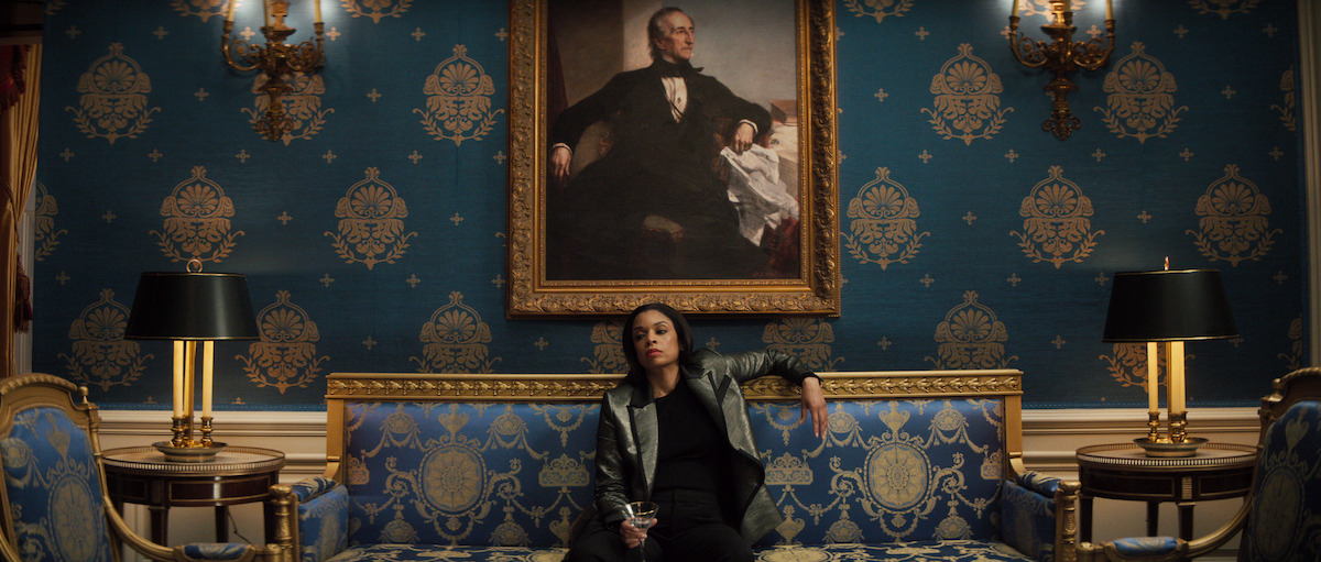 Miss Haney in the Blue Room sitting on a sofa with a drink in hand.