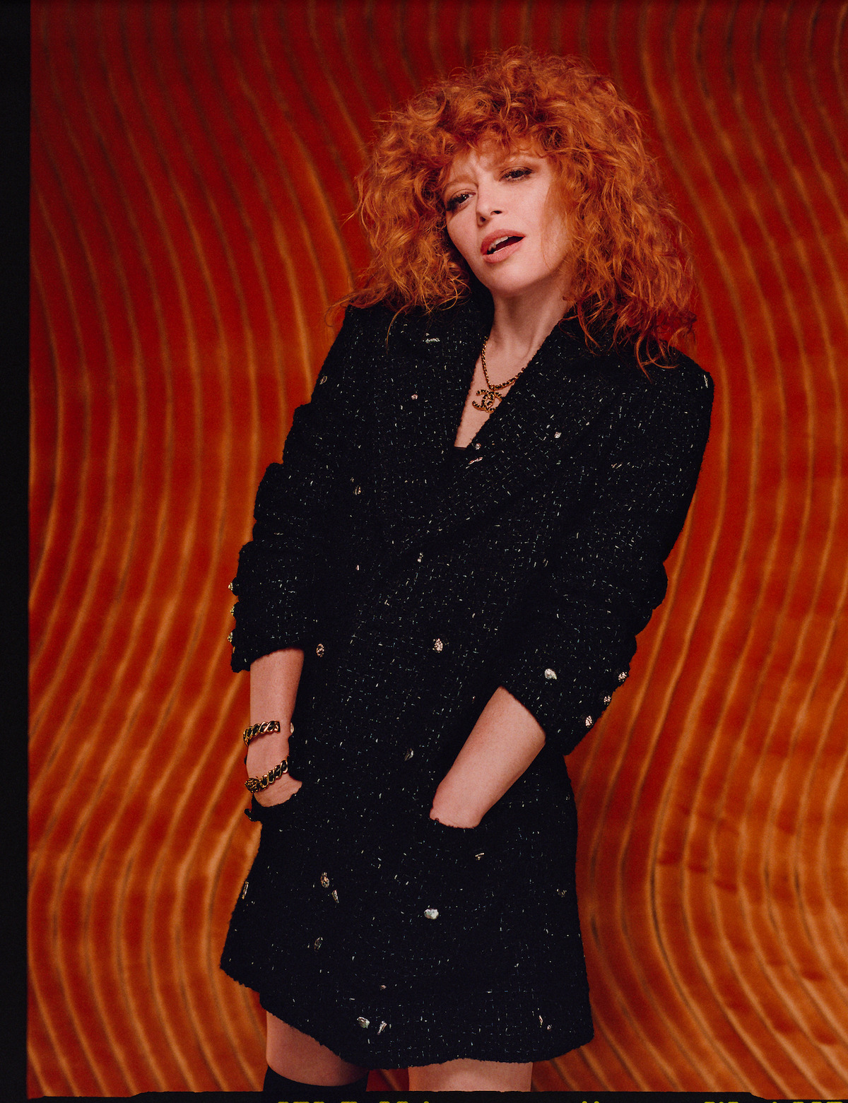 Natasha Lyonne poses against a red background wearing a sequined ensemble.