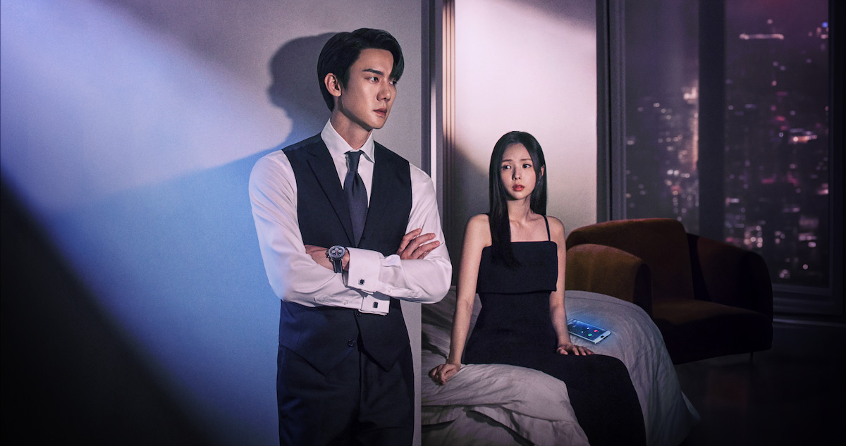  Yoo Yeon-seok and Chae Soo-bin stand next to each other in a high-rise apartment wearing black dinner attire in an image from the series ‘When the Phone Rings.’