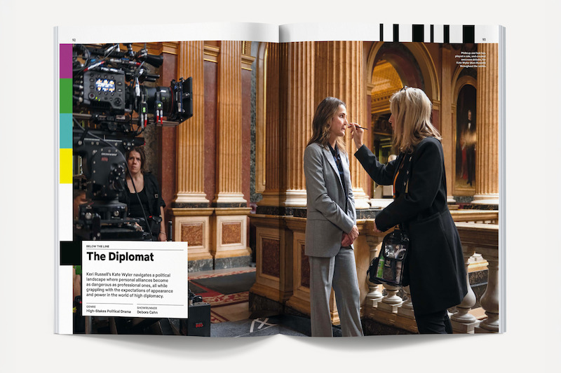 Behind-the-scenes of a TV show filming in an ornate hall, with a camera crew, an actor in a suit getting makeup touch-ups from a makeup artist, and gold columns and elegant decor in the background.