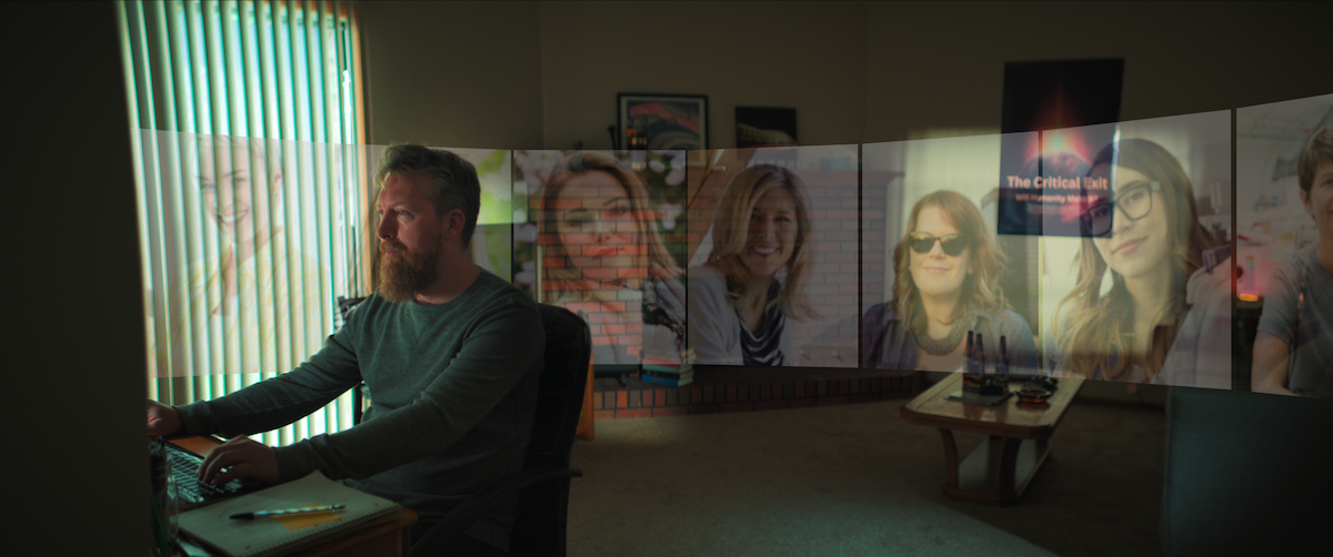 Man at computer with photos of women projected behind him.
