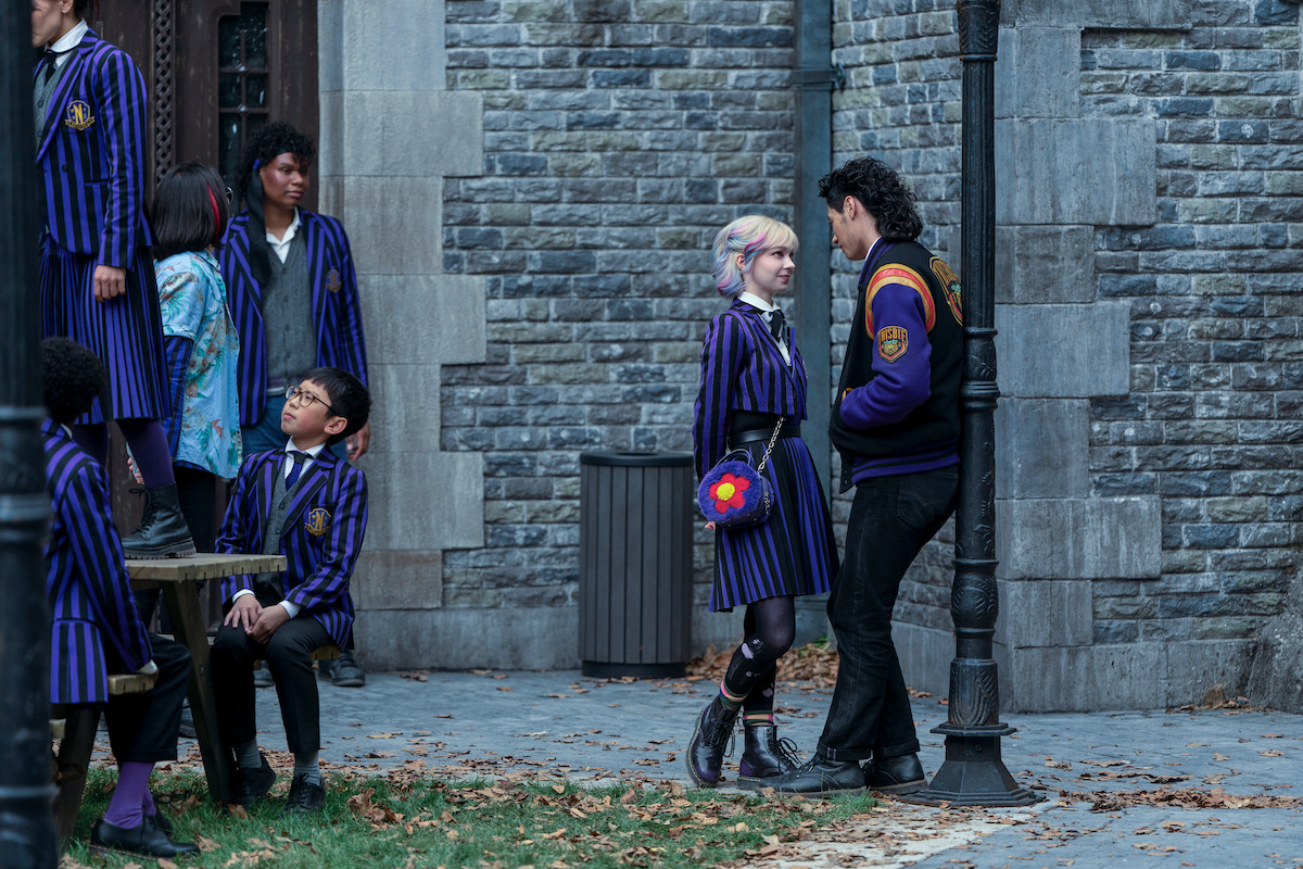 Emma Myers as Enid Sinclair and Noah B. Taylor as Bruno stand close to each other at Nevermore Academy in ‘Wednesday’ Season 2.