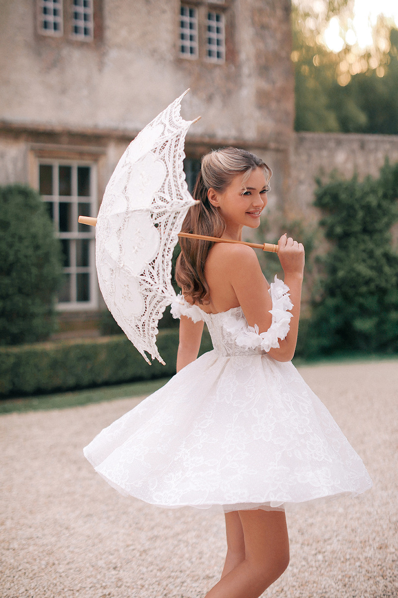 Woman in bridal dresses poses and looks off into the distance.