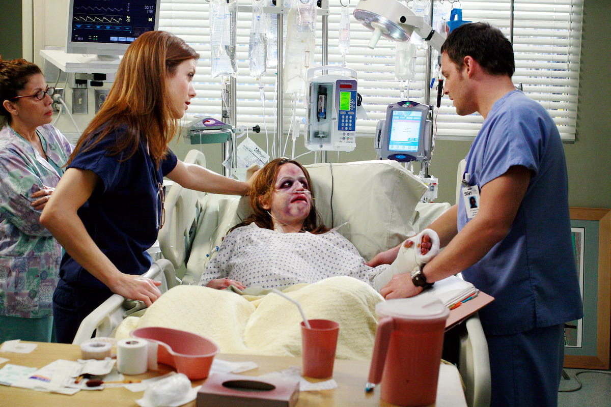 Doctors look down concerned at a patient who has a bruised and swollen face. 