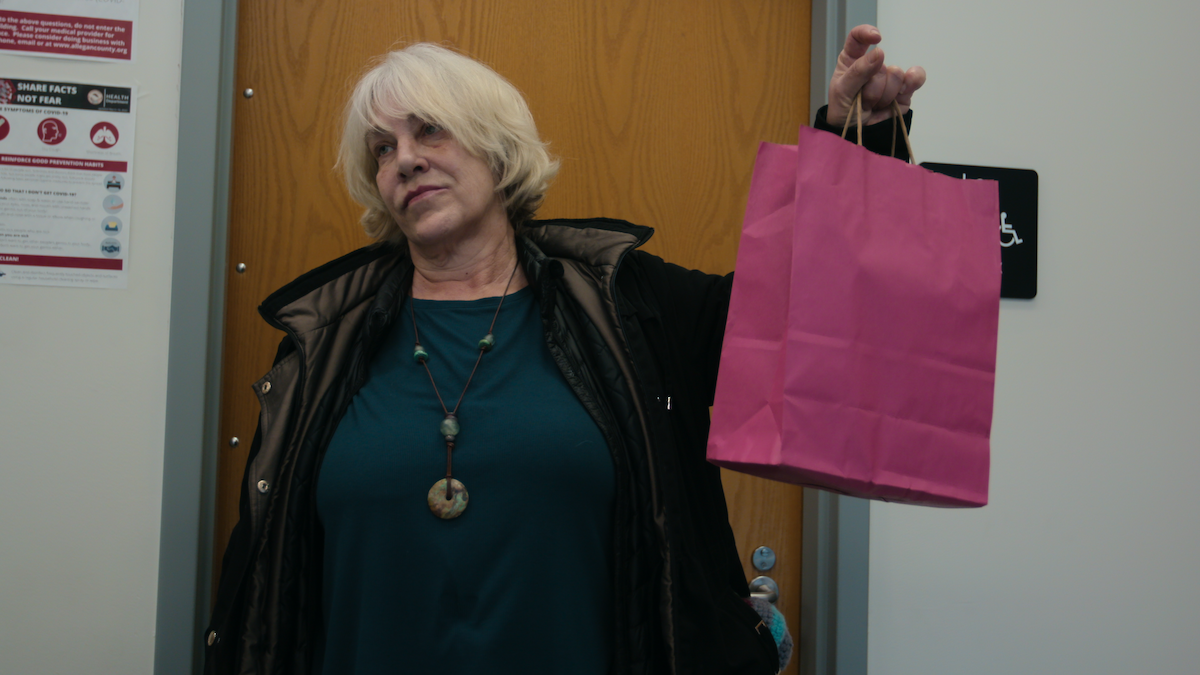 Cathy Terkanian holding up a pink paper bag.
