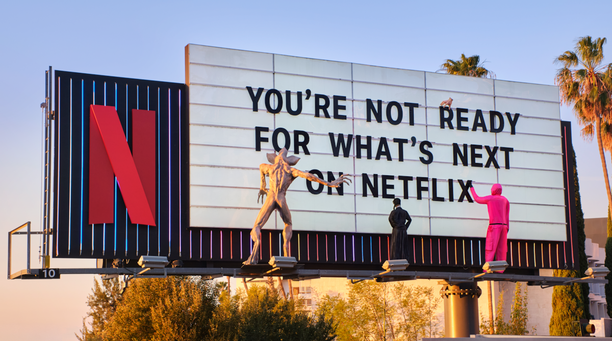 Sunset Blvd Next on Netflix ‘ You’re Not Ready for What’s Next on Netflix’ with maniquins from popular Netflix shows on the billboard - including a Squid Game guard in pink, Wednesday Adams and Vecna.