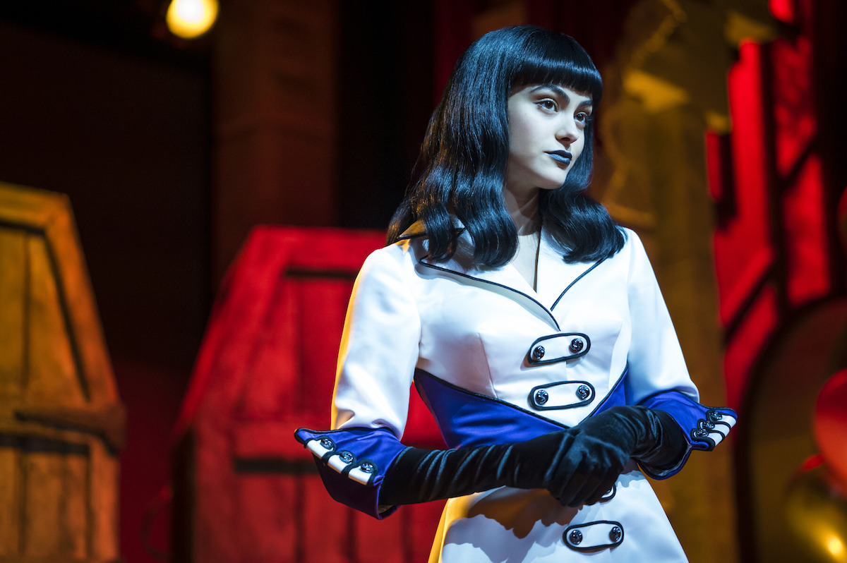 Camila Mendes as Veronica Lodge wears a white coat with long black gloves in Season 7 of ‘Riverdale.’