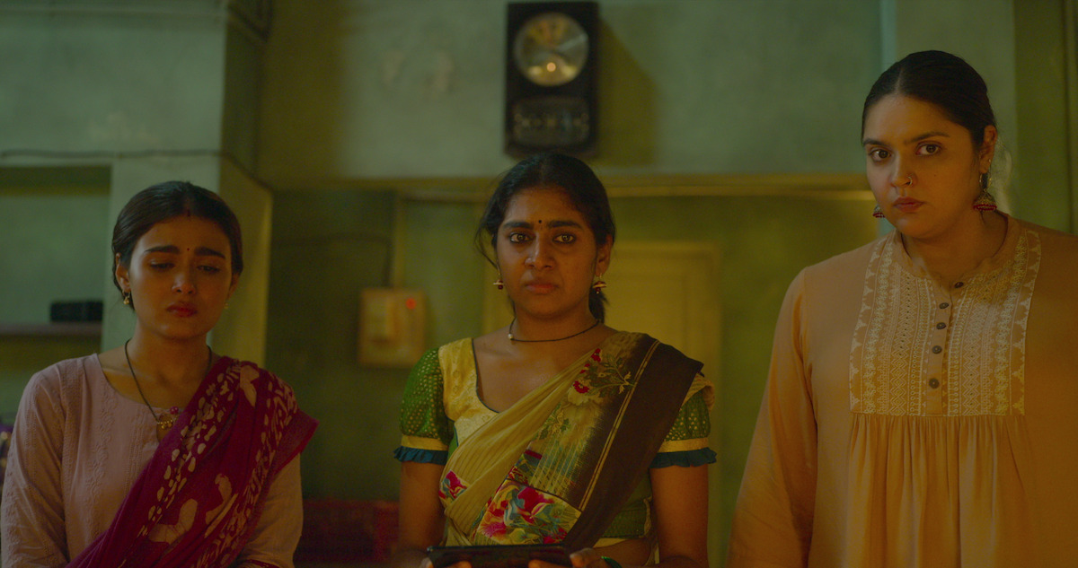 Three women stand looking concerned