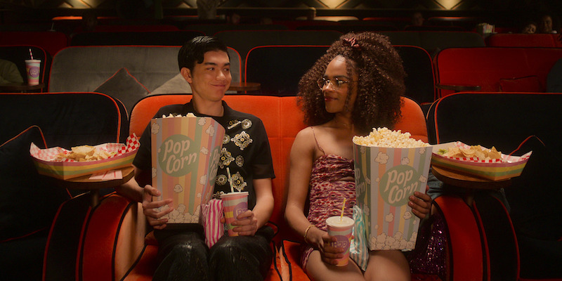 Two people holding popcorn watching a movie