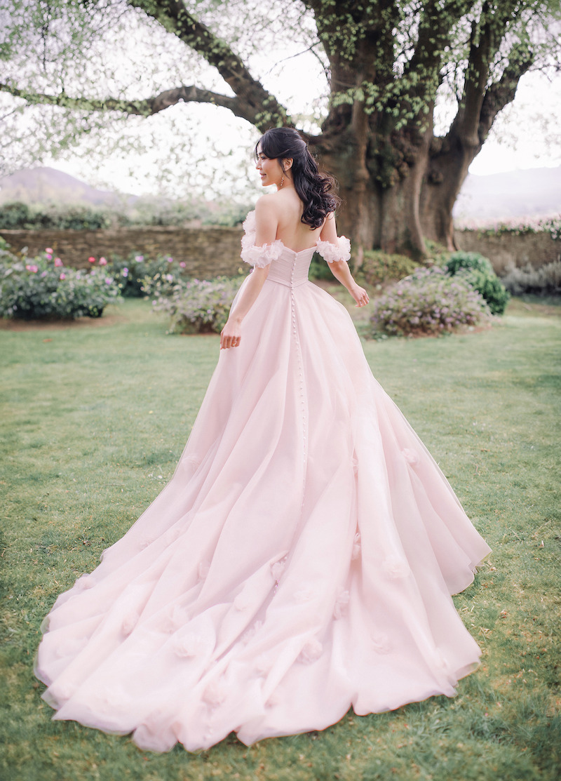 Woman in bridal dresses poses and looks off into the distance.