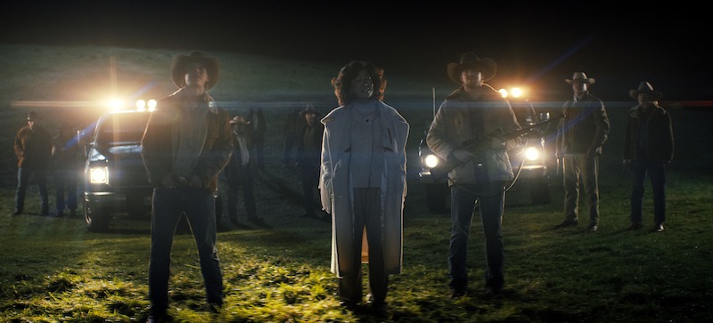A group of of silhouetted figures stands in front of car headlights at night in Season 3 of 'Sweet Tooth'