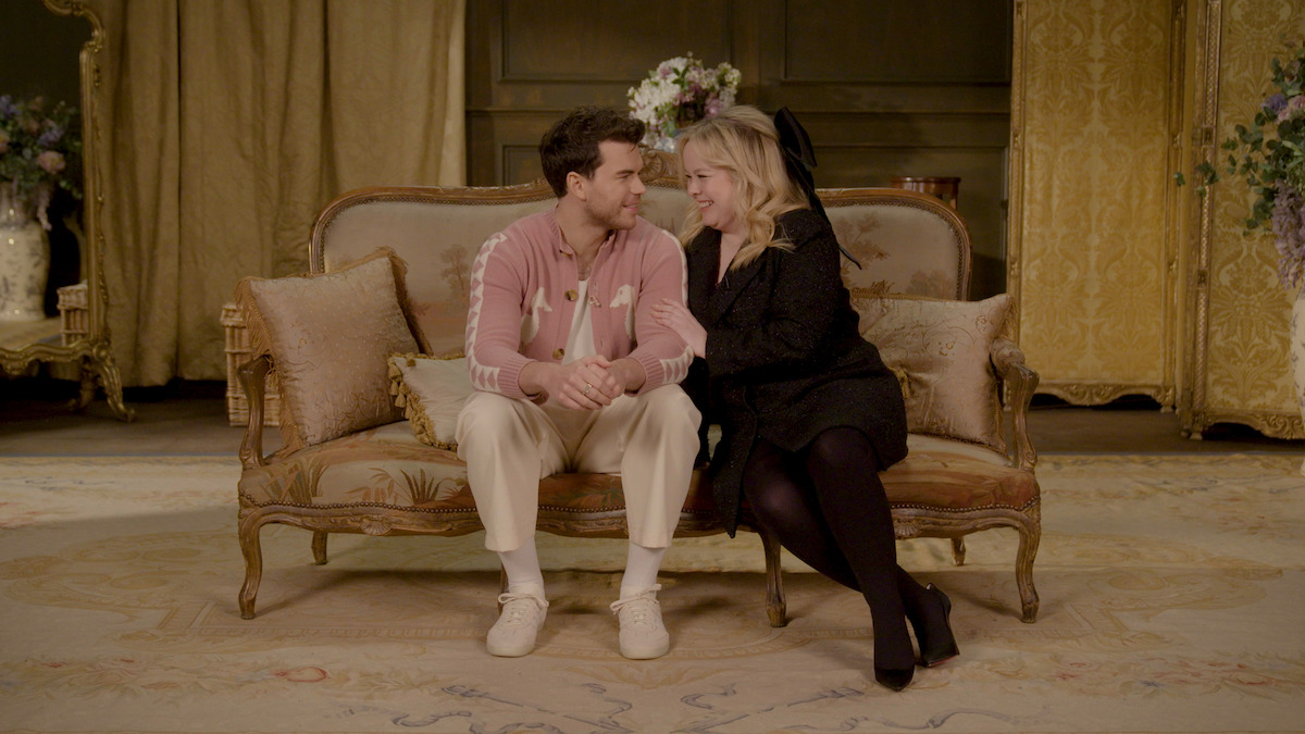 Luke Newton and Nicola Coughlan sit on a couch together