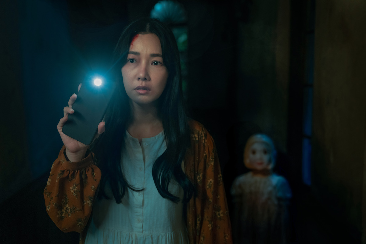 a woman uses her phone as a flashlight to light her way through darkness