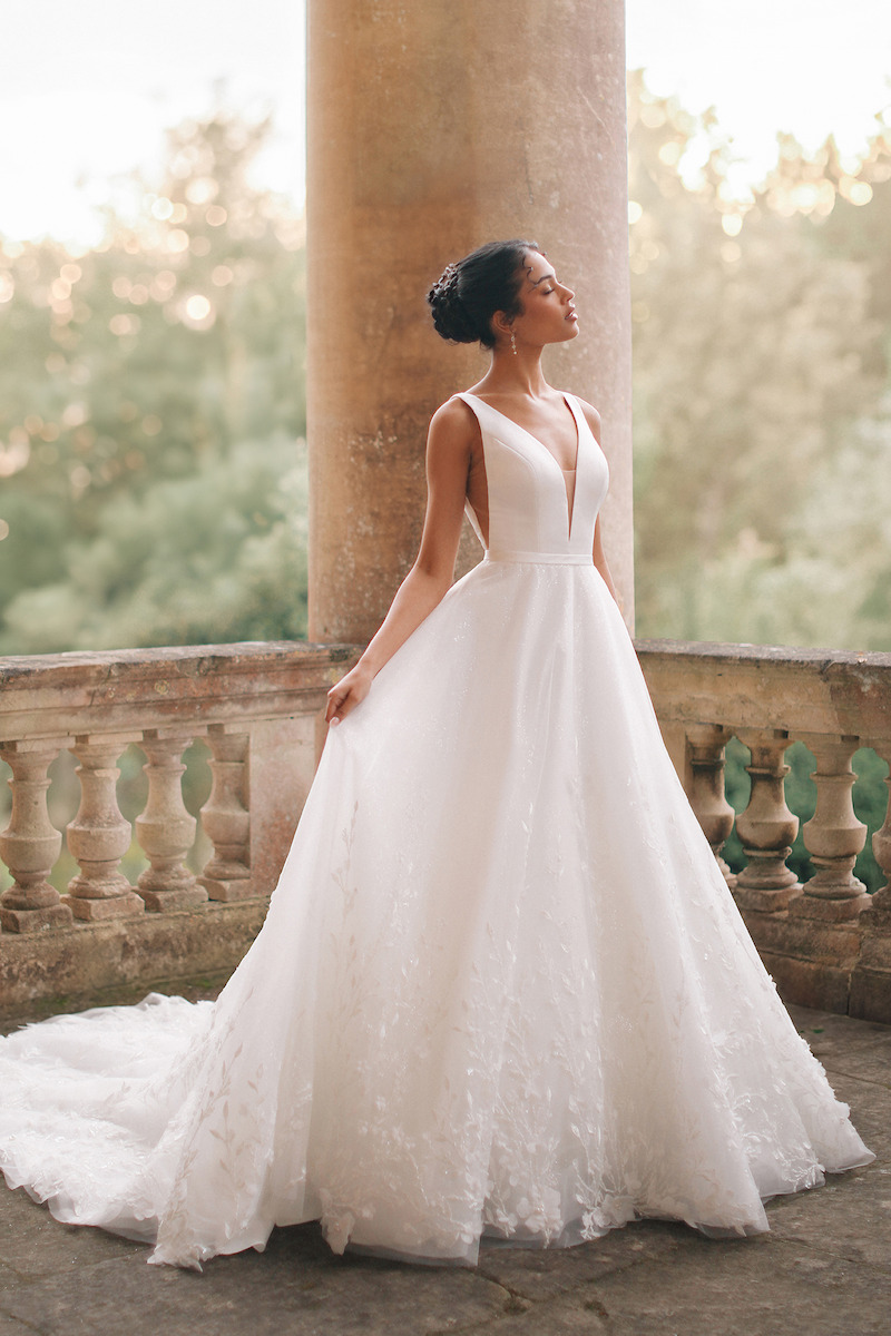 Woman in bridal dresses poses and looks off into the distance.