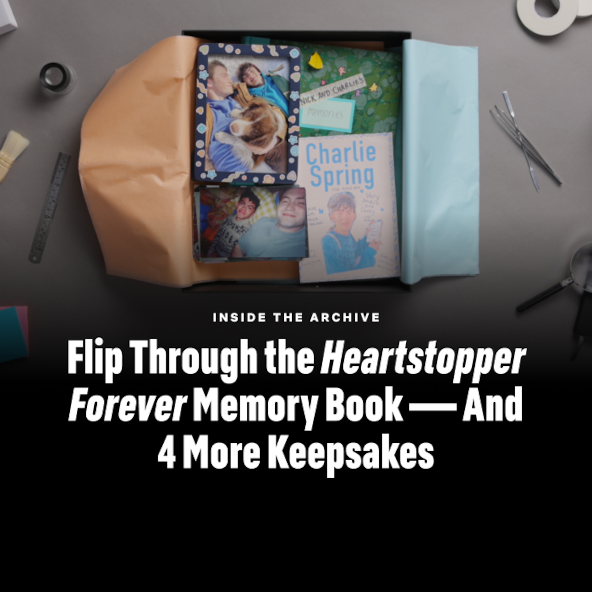 Box with Heartstopper Forever memory book, photos, and keepsakes on a desk with scissors, tape, and paper; text on right reads "Flip Through the Heartstopper Forever Memory Book — And 4 More Keepsakes."