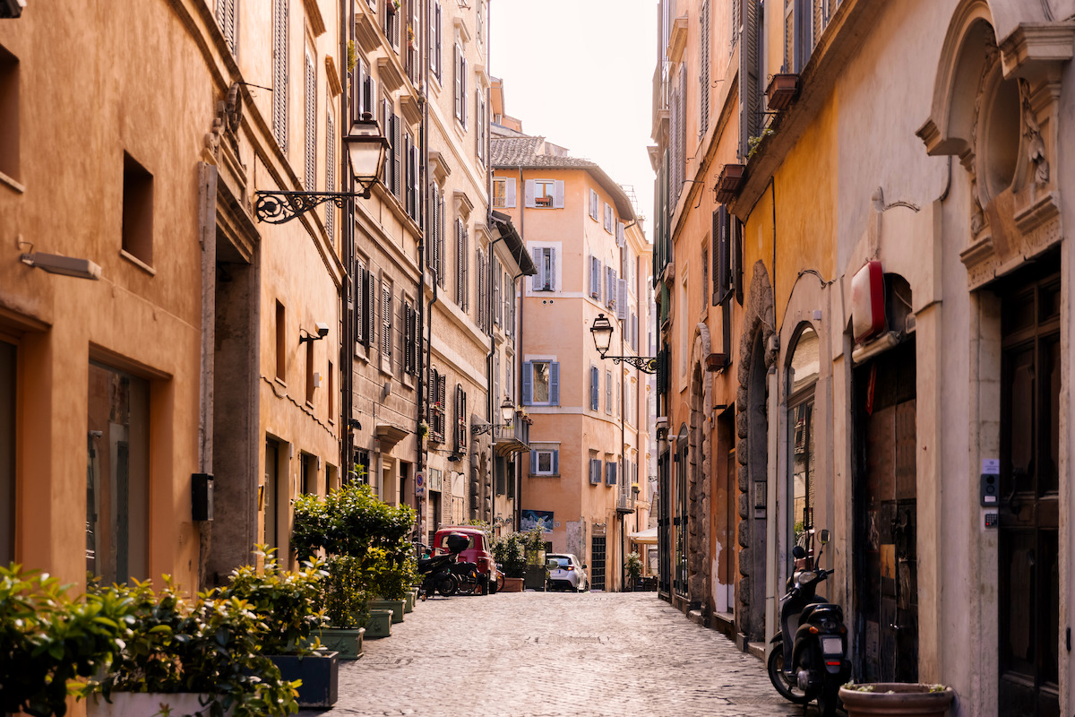 Narrow cobblestone street lined with colorful historic buildings in Rome, Italy.