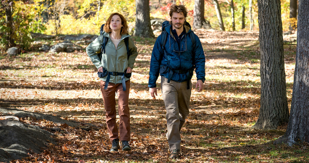 Ellie Kemper and Luke Grimes hike in the woods in a still from ‘Happiness for Beginners.’