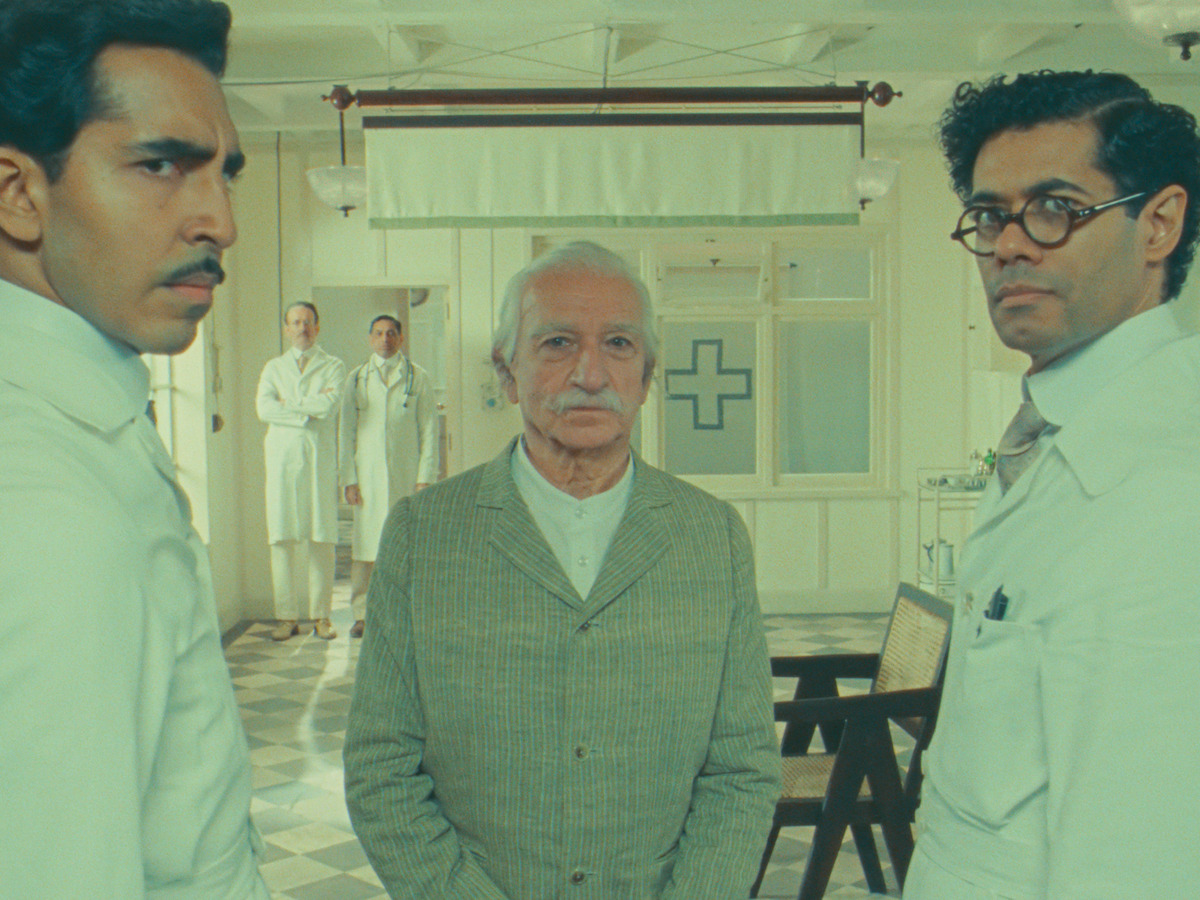 Three men standing in a hospital ward