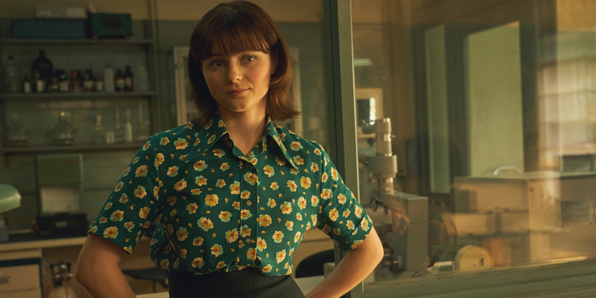 Jean Purdy (Thomasin McKenzie) stands in a green dress with her hands on her hips.