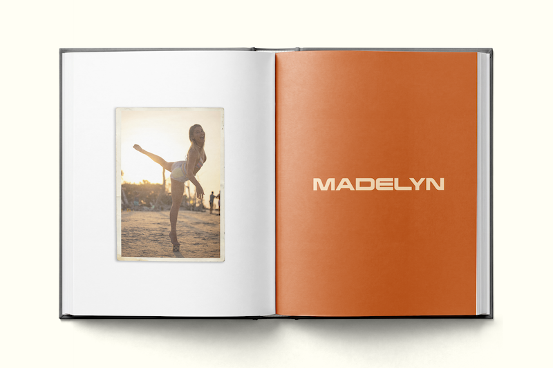 Photo book open to two pages; left page shows a person posing playfully at the beach near sunset, with people and sun in the background; right page is solid orange with the name "MADELYN" printed in large, bold letters.