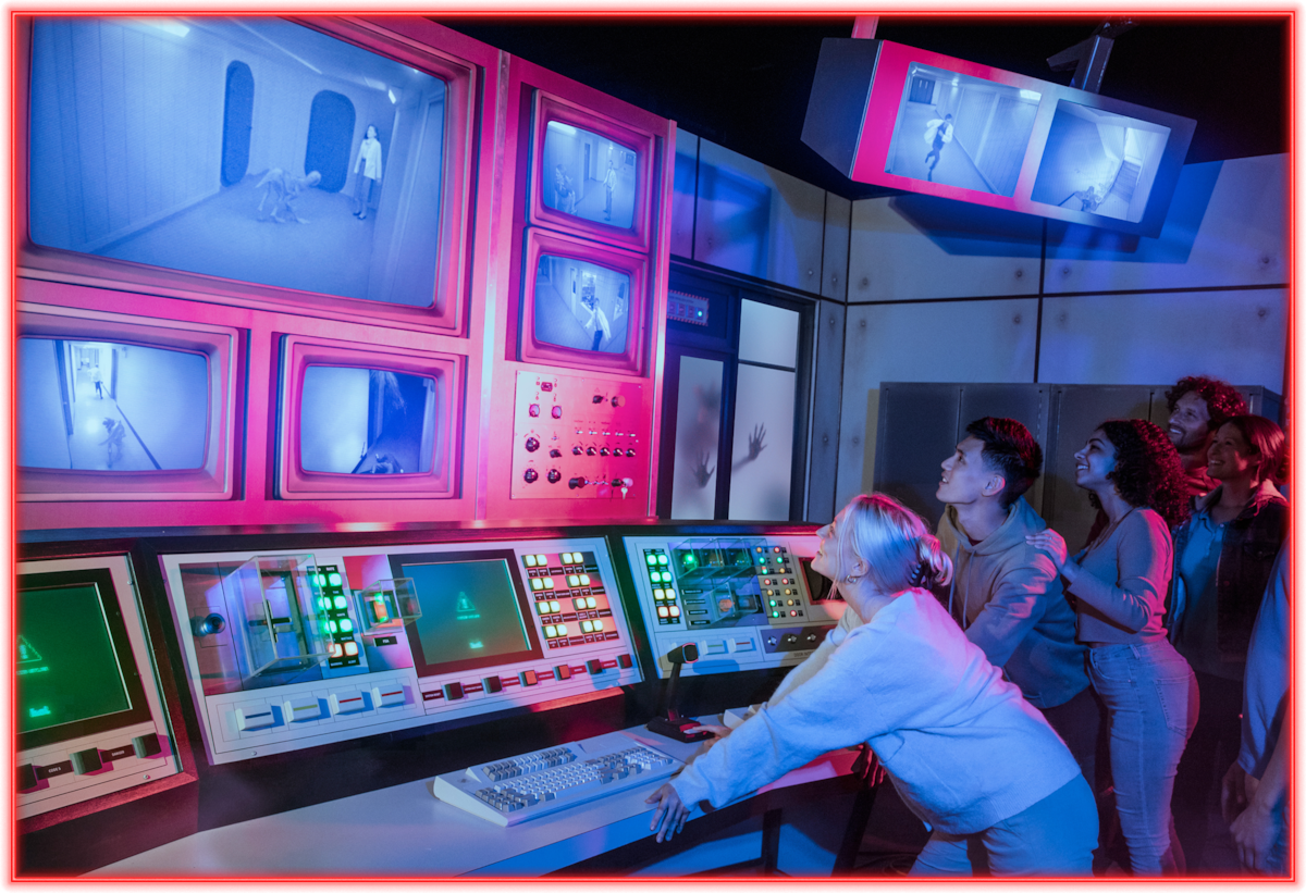 A group of people in a dimly lit control room watch large surveillance monitors showing a figure in a hallway, hands on the control panels, appearing engaged or intrigued, with glowing buttons and dramatic blue-pink lighting.