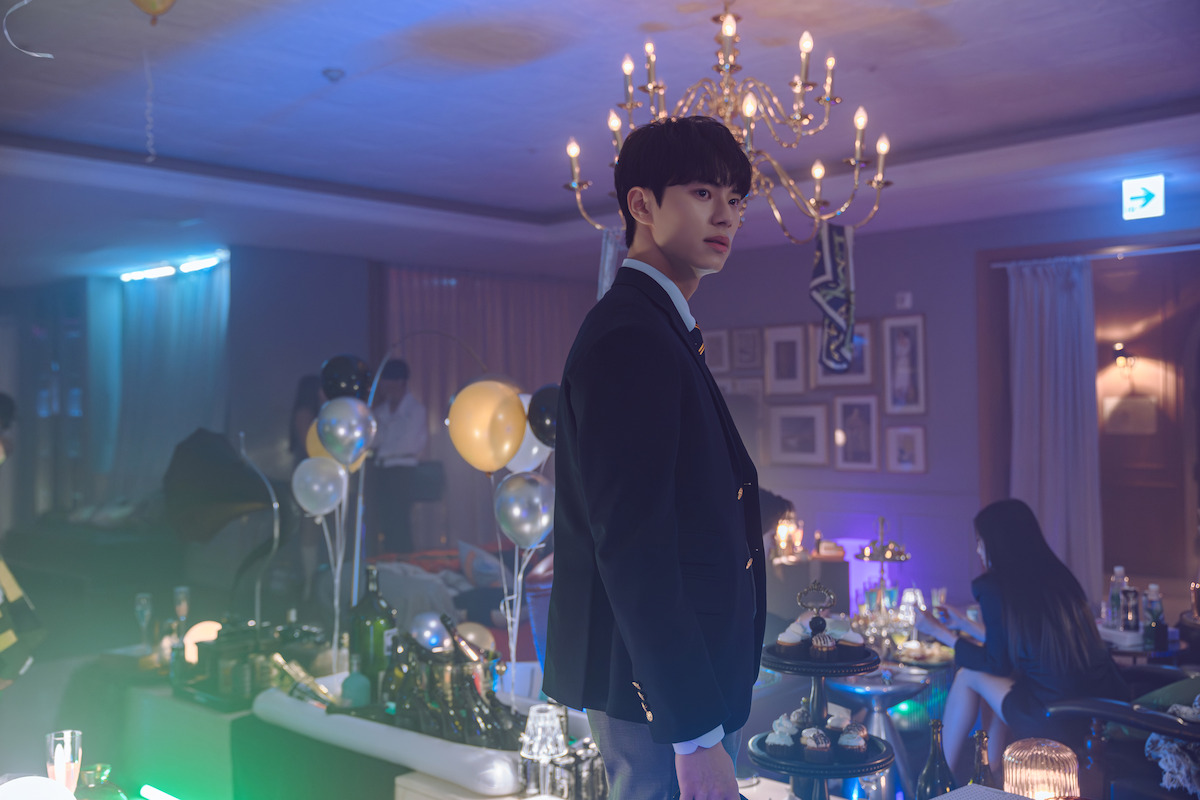 Lee Chae-min as Kang Ha stands in the middle of a party in an image from the series ‘Hierarchy.’