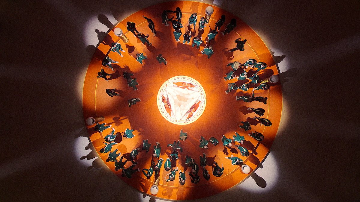 Overhead view of people in teal uniforms standing in a circle around a lit central area on an orange floor, casting long shadows; symmetrical, intense, and suspenseful atmosphere.