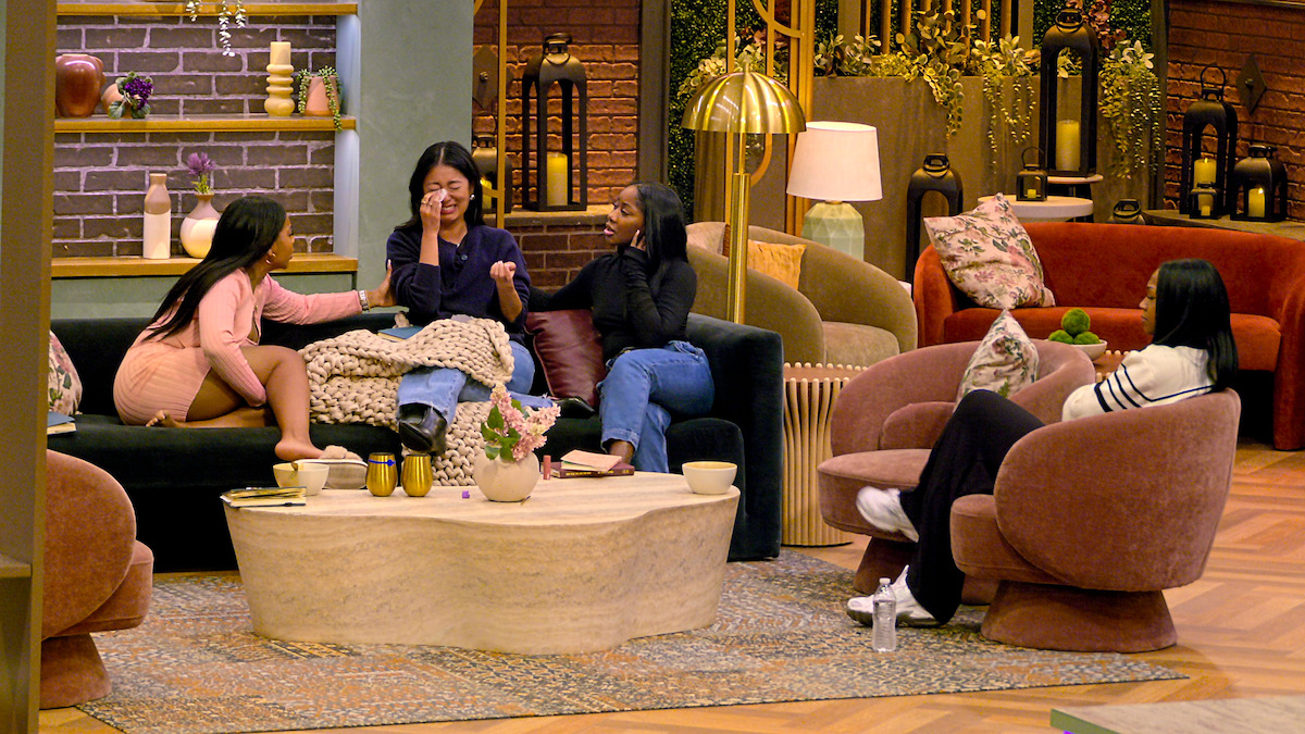 Keya Kellum, Emma Betsinger, Dynasty Ballard, and Tyler Lanier sit and talk in a cozy, modern living room with comfortable chairs, a coffee table, warm lighting, plants, and decorative accents, creating a relaxed and inviting atmosphere.