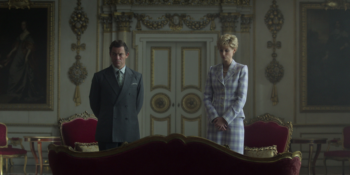 Dominic West as Prince Charle and Elizabeth Debicki as Princess Diana stand far apart from each other in a room of a palace in Season 5 of ‘The Crown’